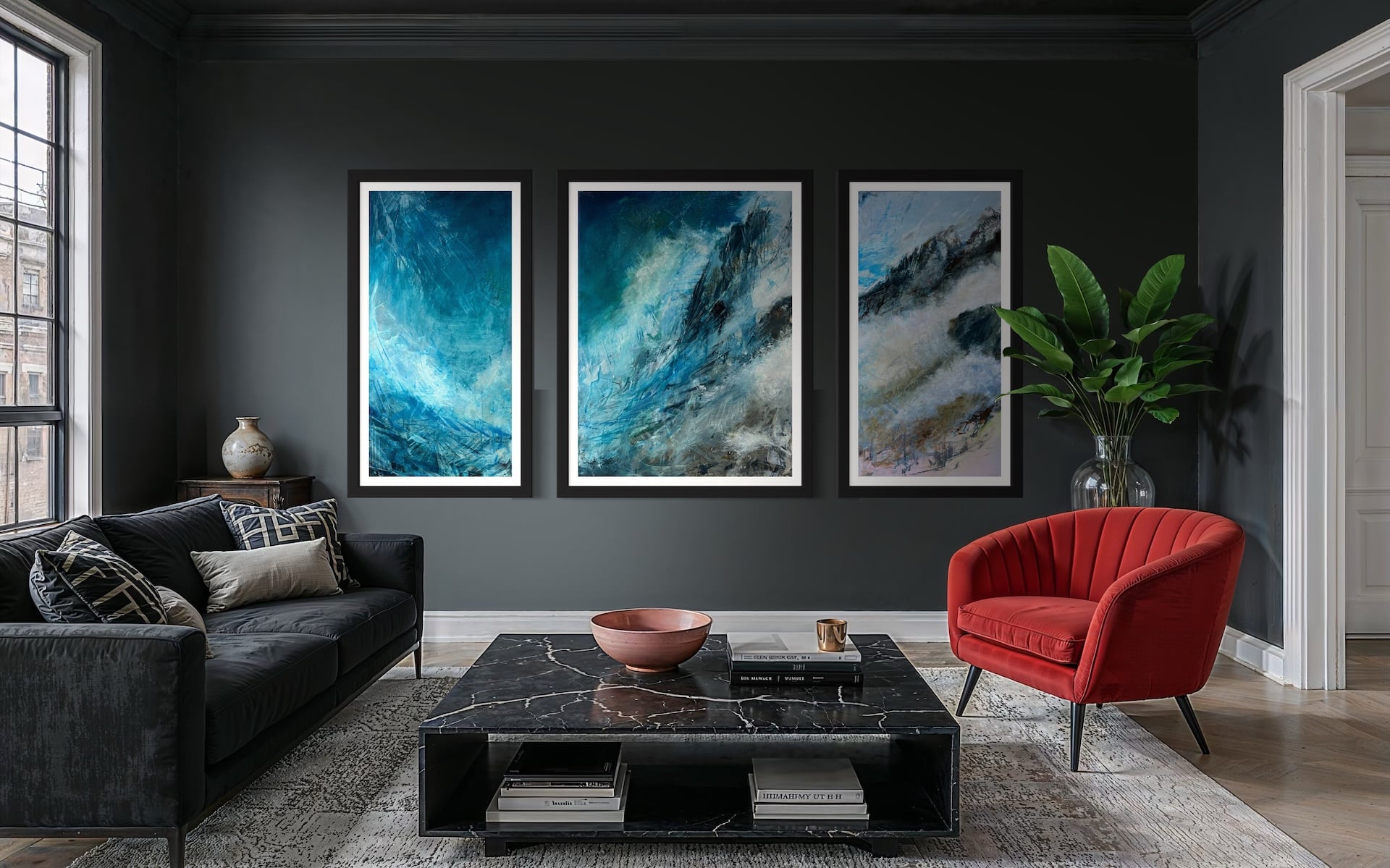 Ascent triptych by Cynthia McLoughlin displayed in a modern living room with dark walls. The three abstract panels feature dynamic blue, teal, and white brushstrokes, evoking the movement of mist over mountains. The artwork is framed in black and hans above a black marble coffee table, with a red accent chair and green plant nearby.