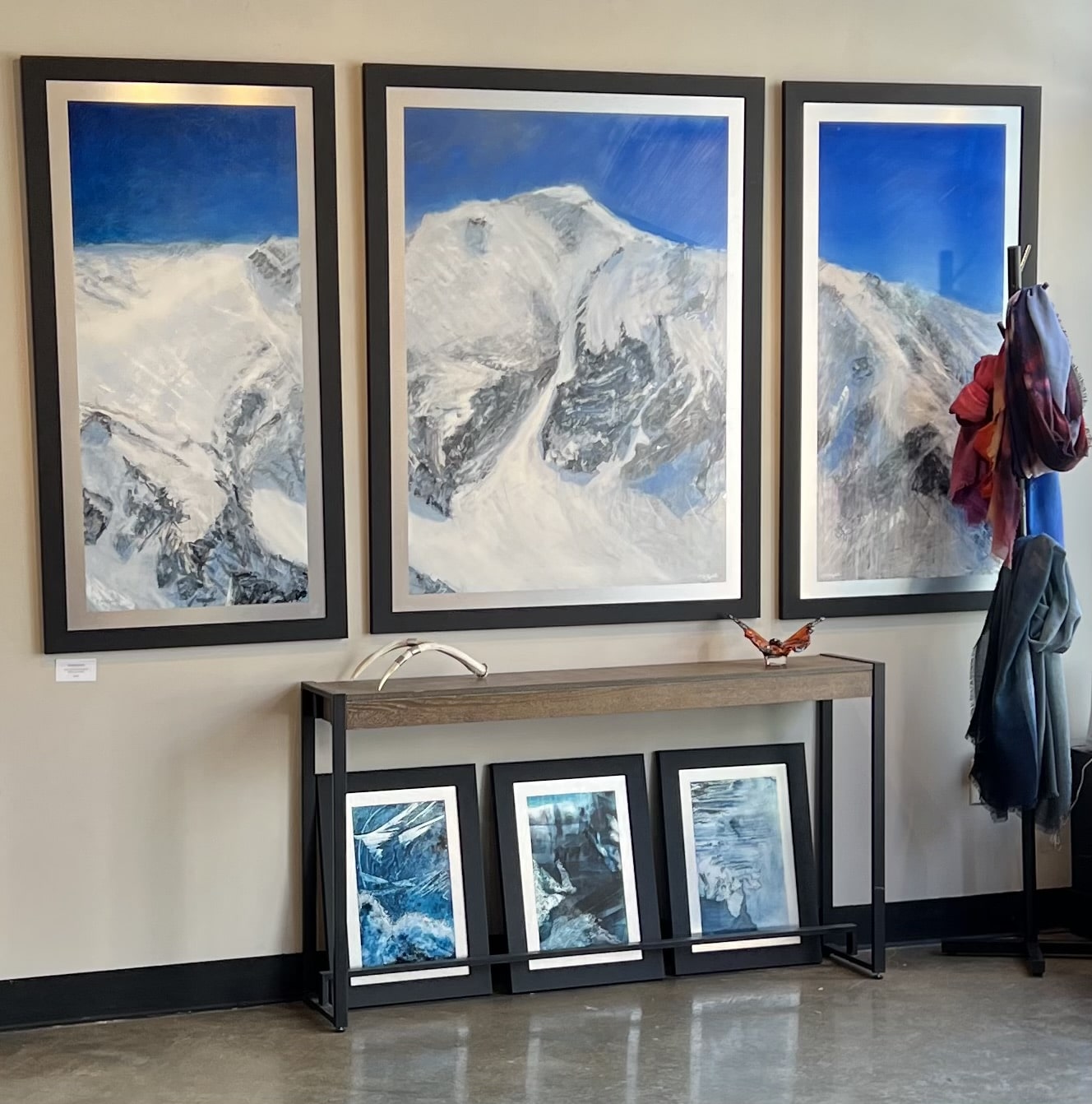 Triptych Landscape oil painting of the iconic Pipeline chute in Utah's Wasatch Mountains, featuring a steep, dramatic ski line beneath an expansive, glowing sky rendered in expressive, layerd tones of deep blue. in the Summit Gallery in Park City, Utah.