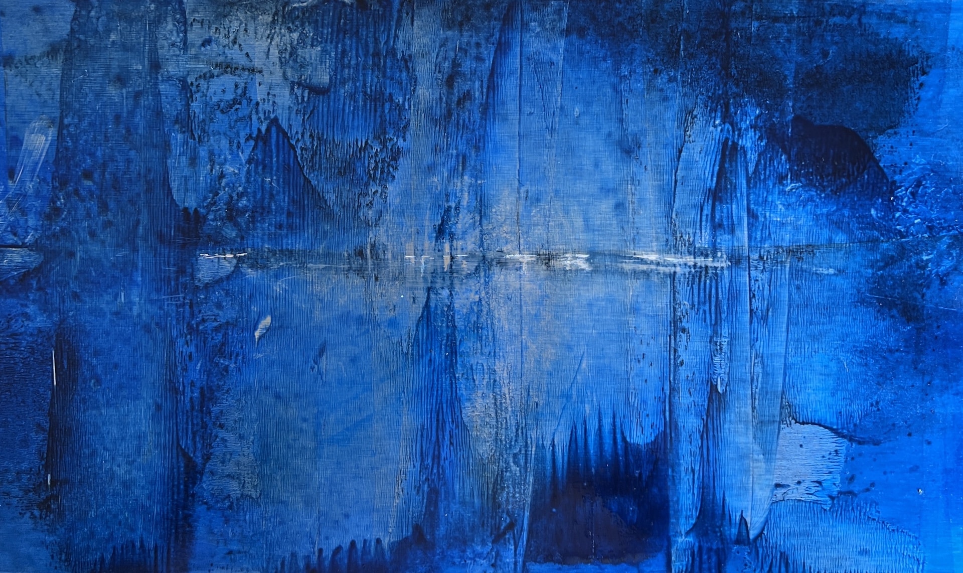 Horizontal abstract painting in layered cobalt and deep blue with a narrow pale horizon-like line suggesting distant water, light and atmospheric space.